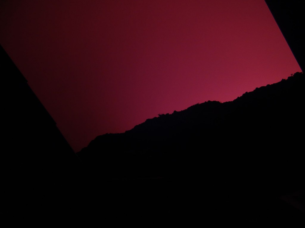 Red glowing night over the huts on the rim of the crater